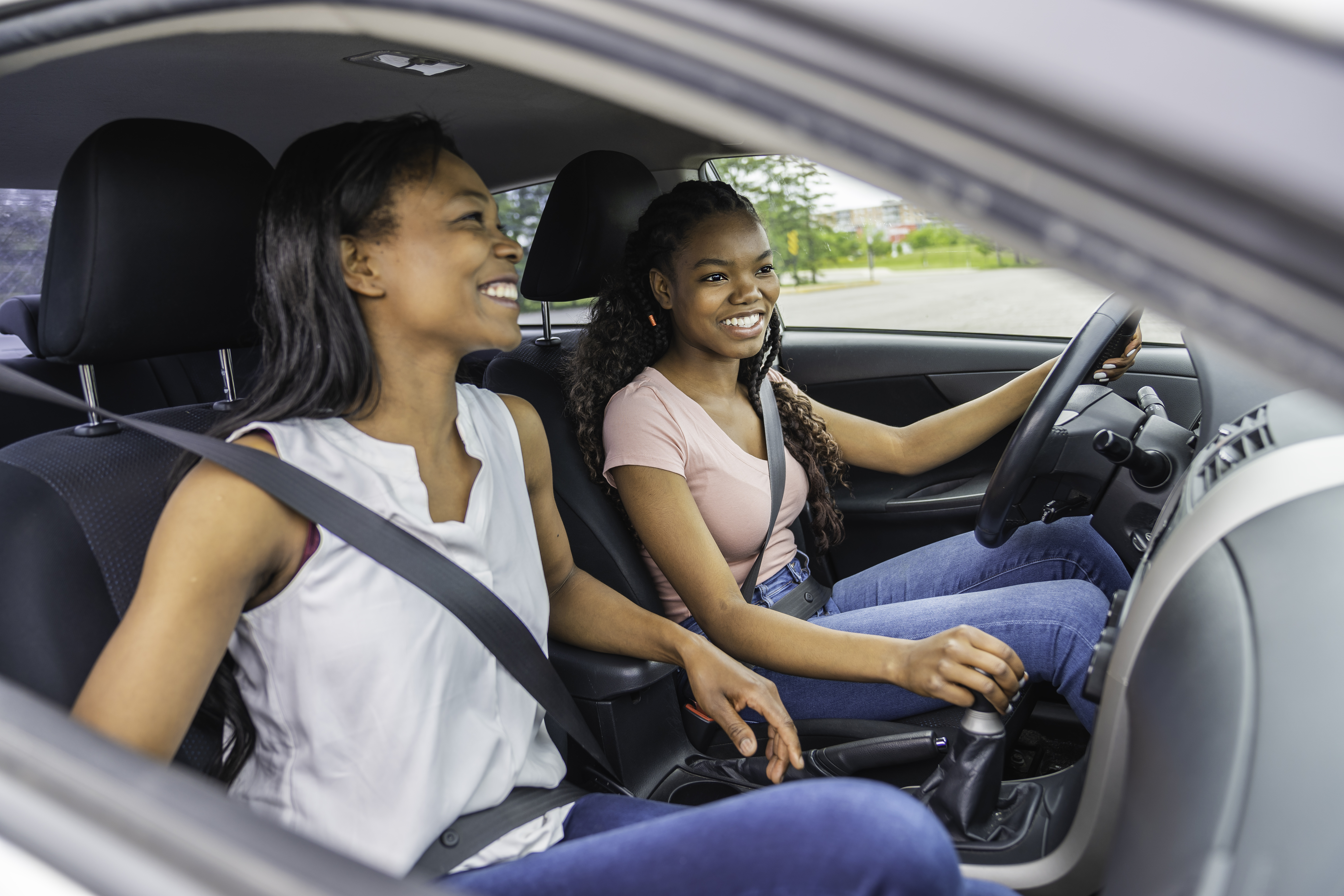 Jeune conductrice adolescente noire assise dans sa nouvelle voiture avec sa mère